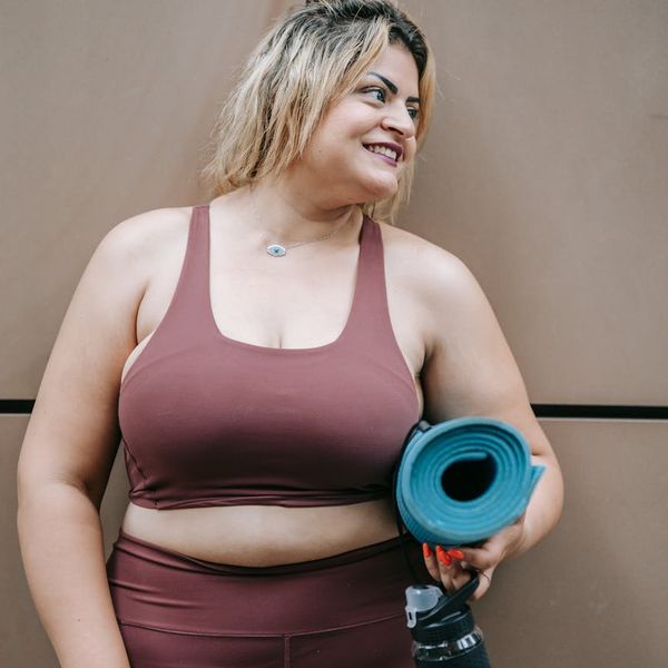 Smiling person unrolling a yoga mat in a bright studio.